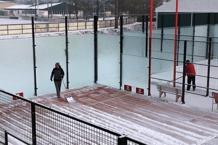Snow-Covered Padel Court Without Weather Protection – Need for Courtcovers All-Weather System Snow-covered padel court without a Courtcovers Padel Court Cover, showing the labor required to clear the snow and the need for all-weather protection to safeguard the padel carpet.